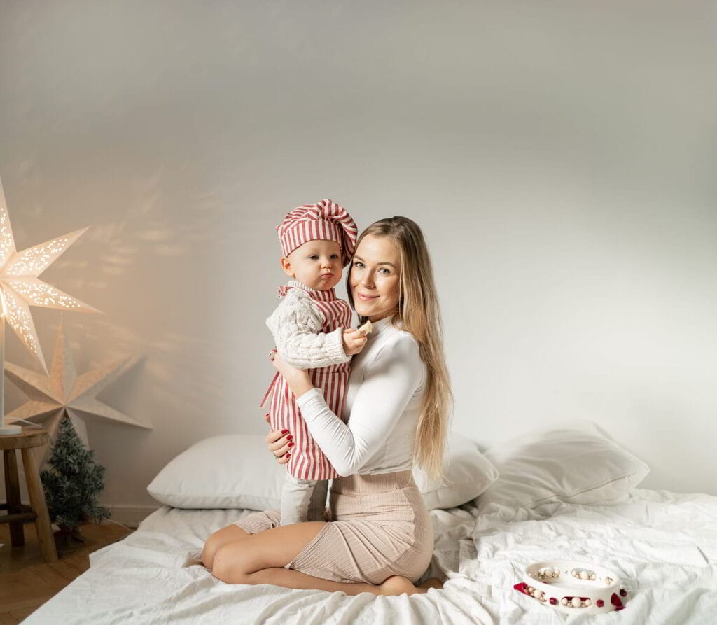 kobieta w studio fotograficznym pozuje do zdjęcia z dzieckiem na rękach