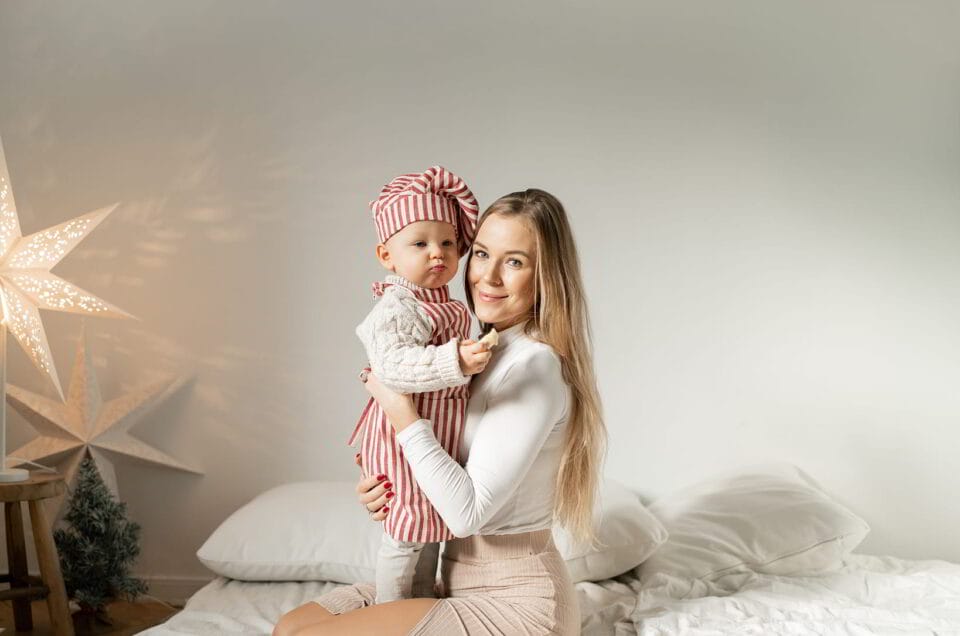kobieta w studio fotograficznym pozuje do zdjęcia z dzieckiem na rękach