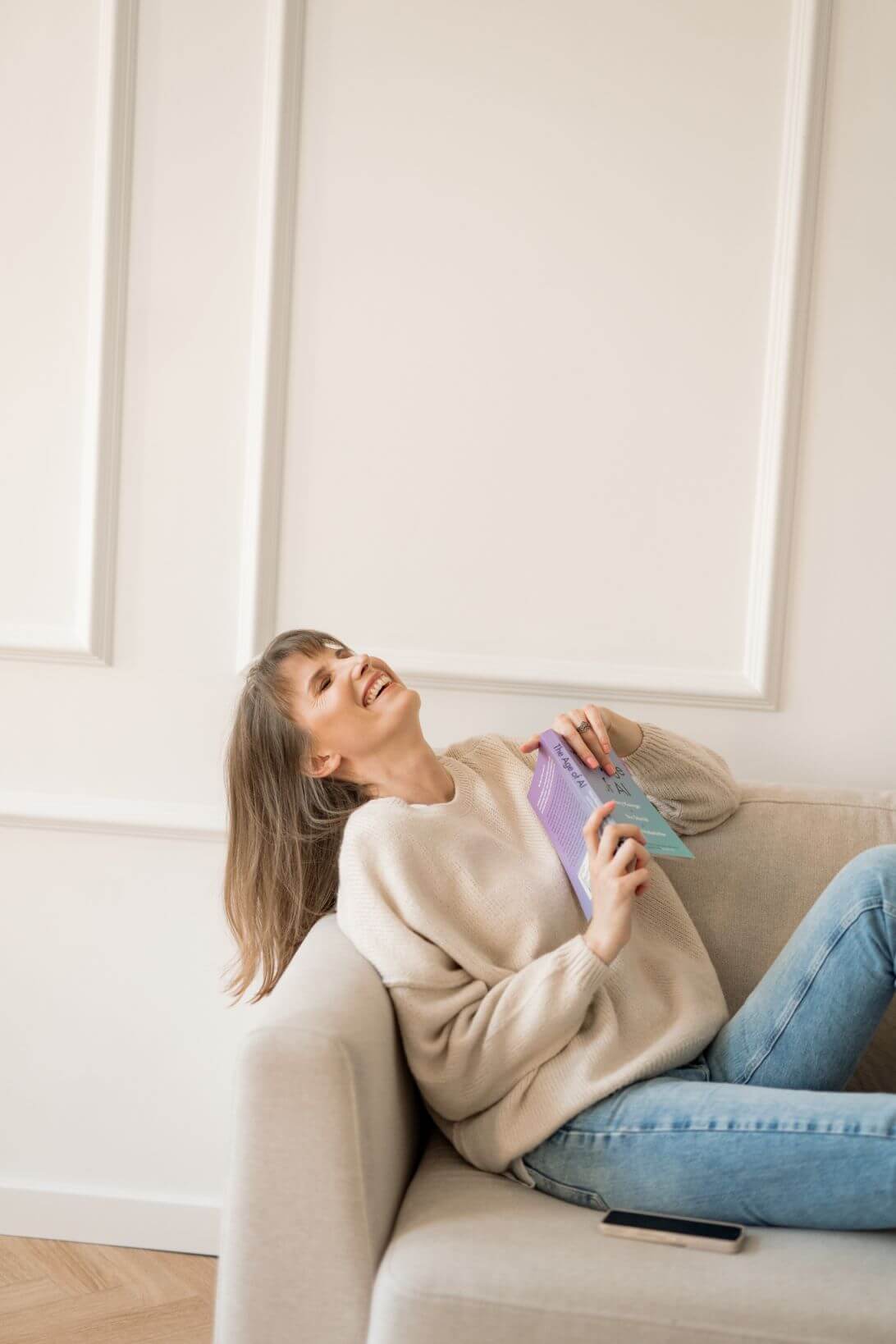 Kobieta siedząca na kanapie i uśmiechająca się.