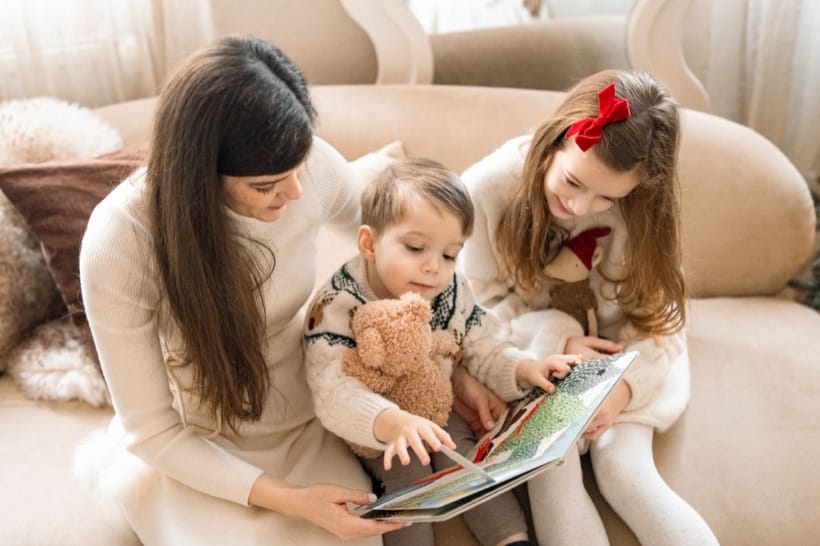 Mother reading a Christmas book with her children — studio session