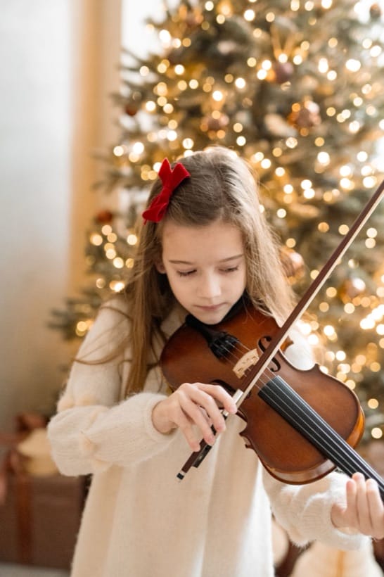 A girl playing the violin by the Christmas tree — Christmas session