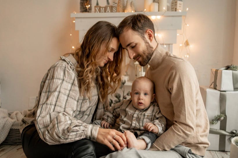 Parents with their child by the fireplace — Christmas studio session